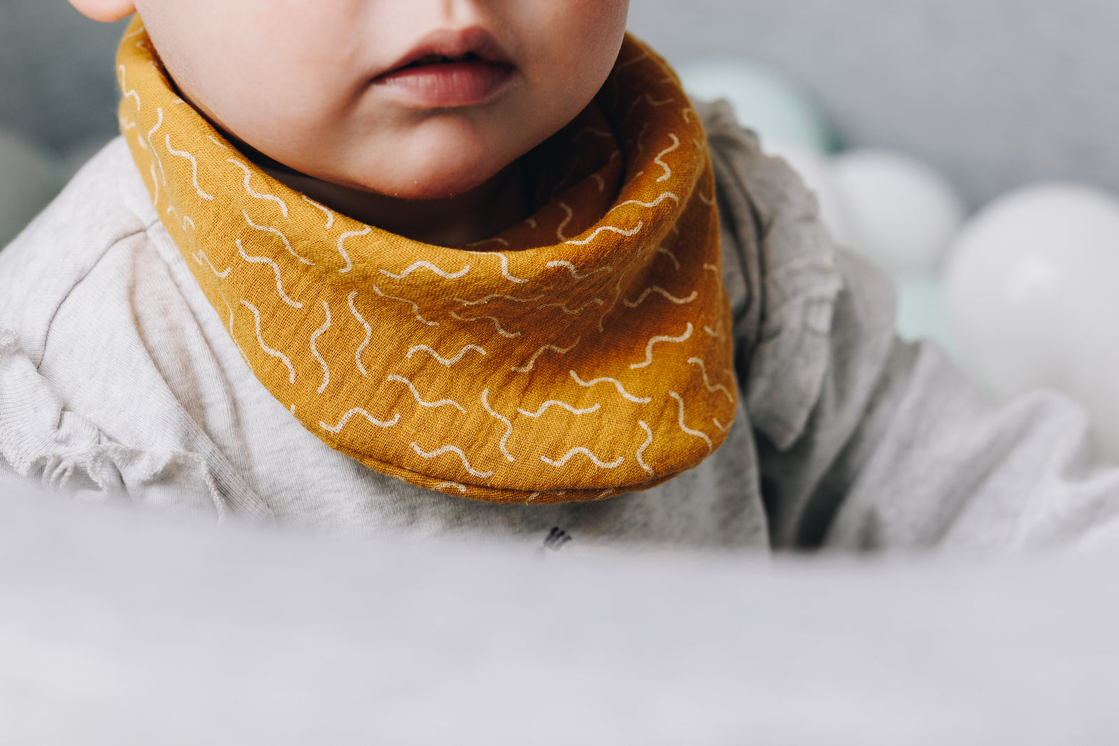 Baby smiling while wearing a Milk + Joy double gauze bib.
